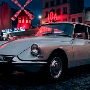 Silver vintage Citroën DS in front of Moulin Rouge neon lights, high-contrast Paris Noir style metal art print.